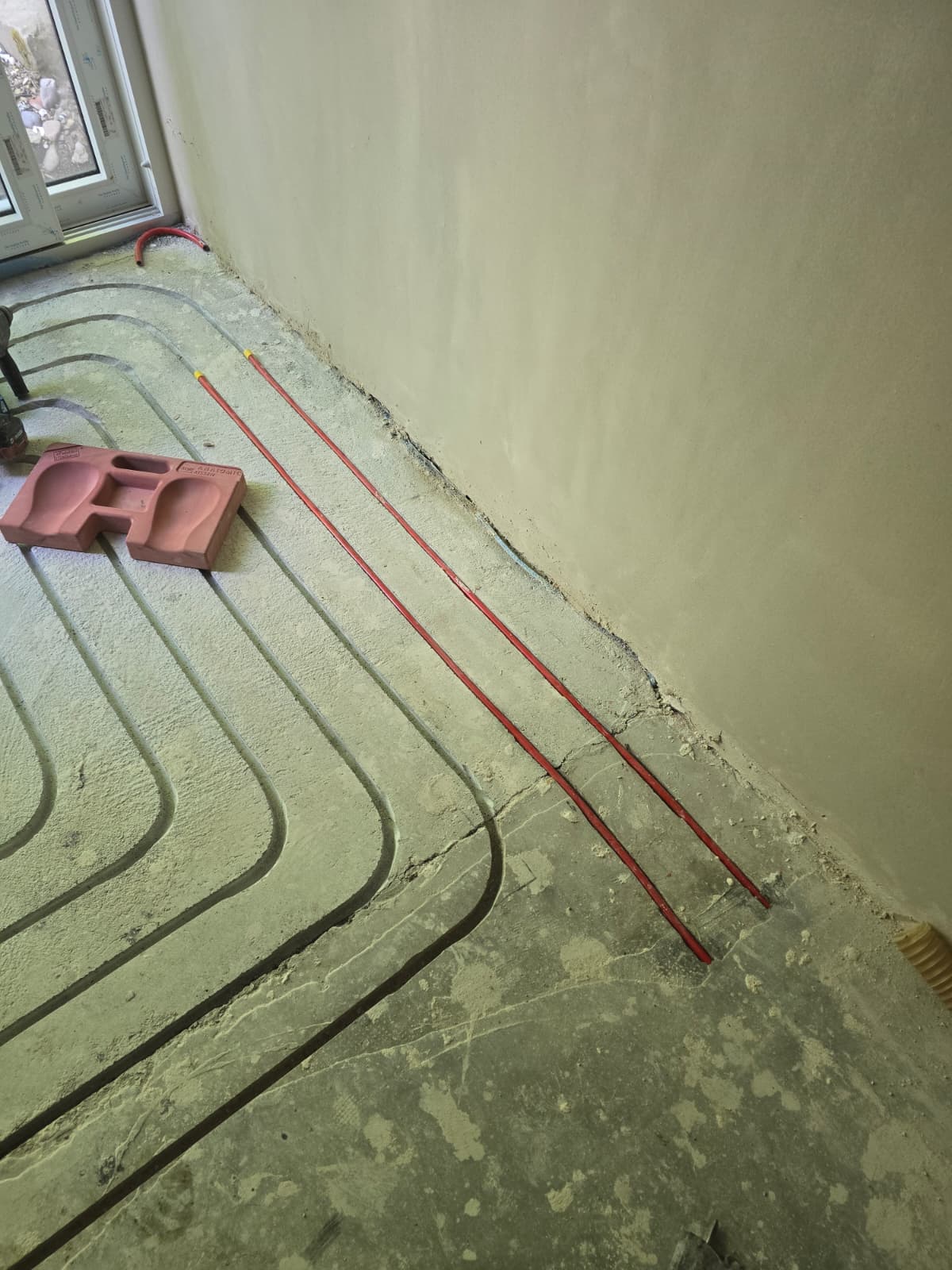 Geöffneter Estrichbereich mit Heizungsrohren und Fittings